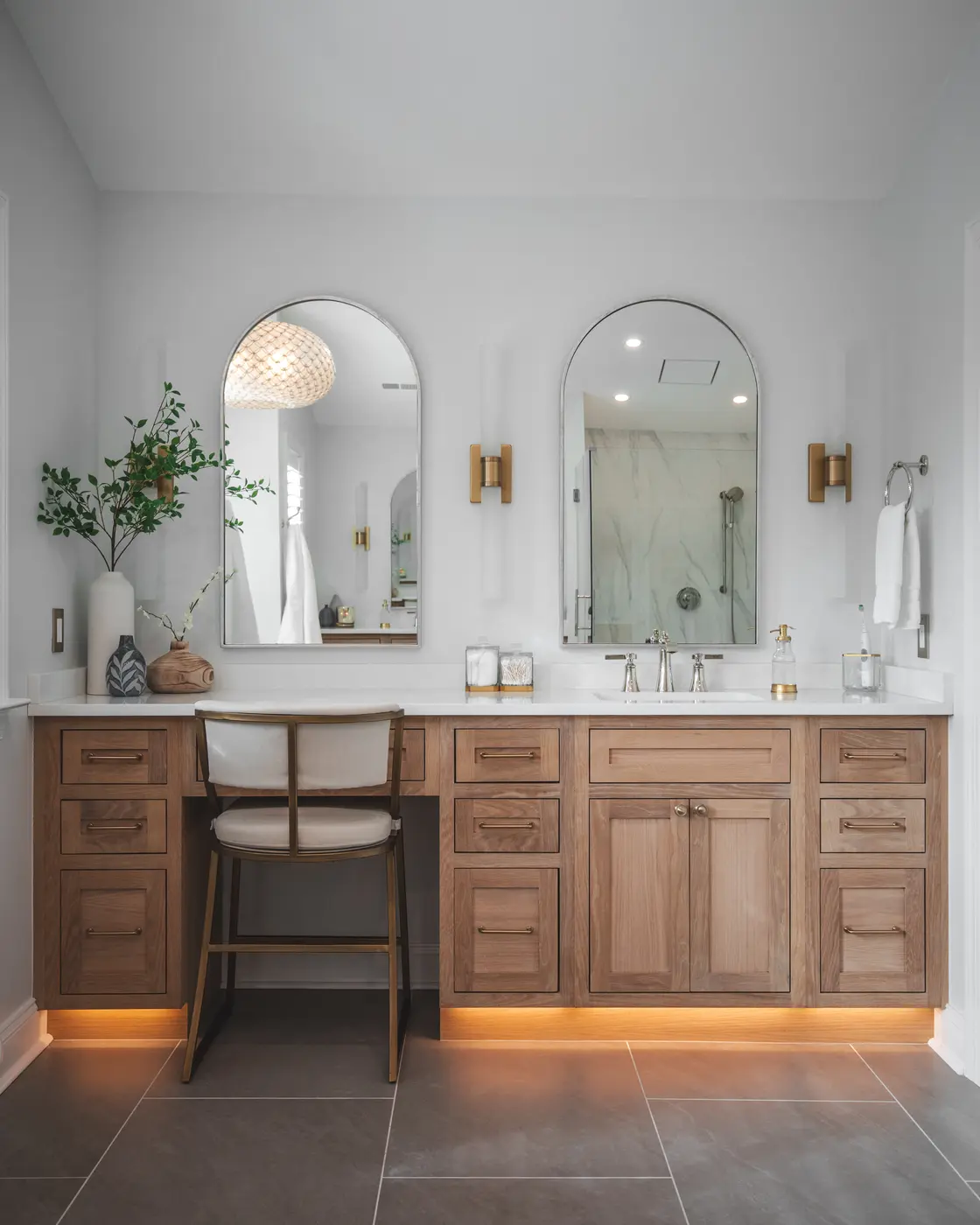 Close-up of bathroom vanity featuring arched mirrors, brass accents, and warm wood cabinetry