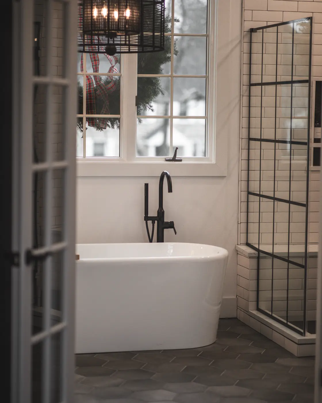 Modern freestanding bathtub with matte black faucet and hexagonal floor tiles