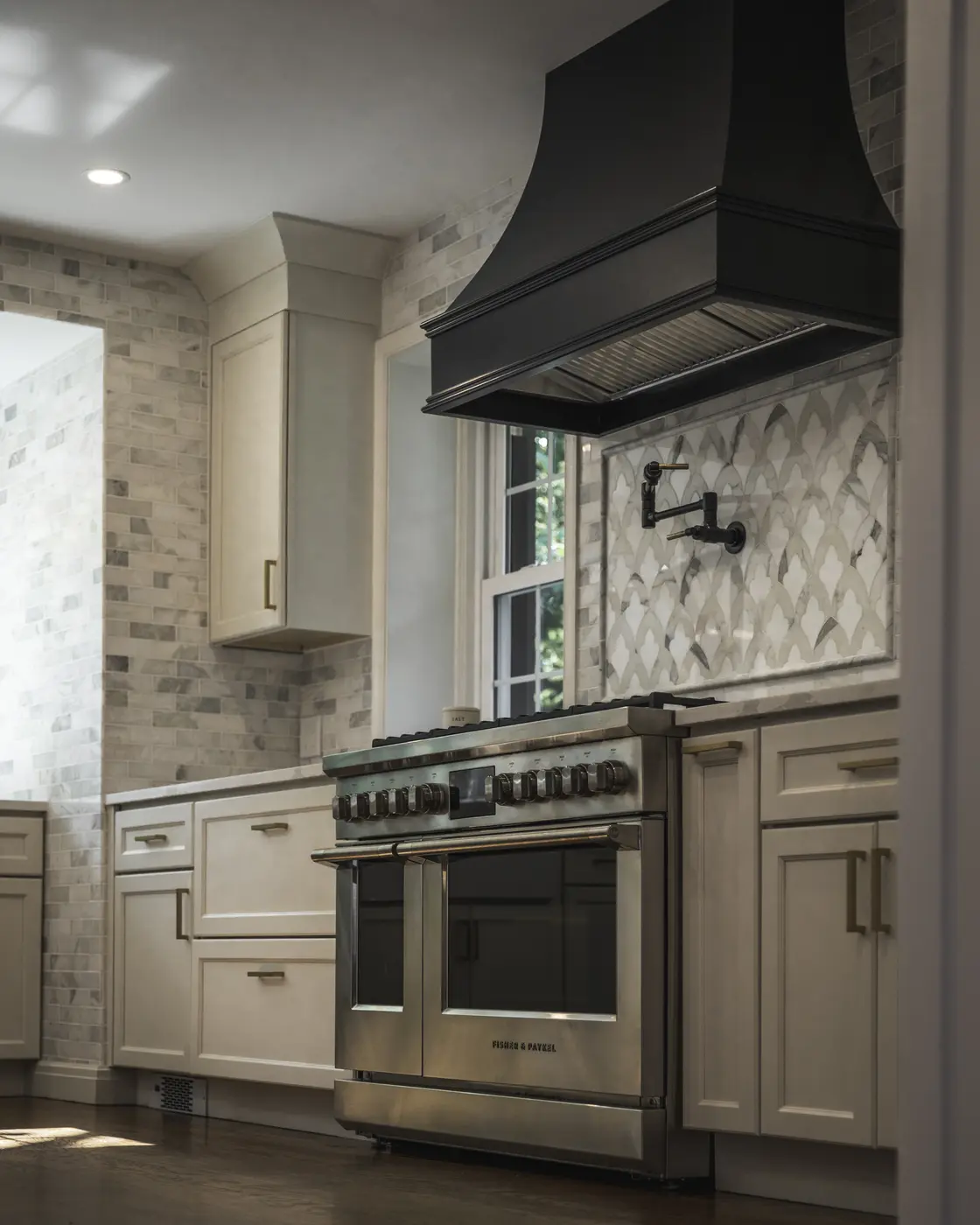 High-end transitional kitchen featuring a matte black hood and stainless steel professional range