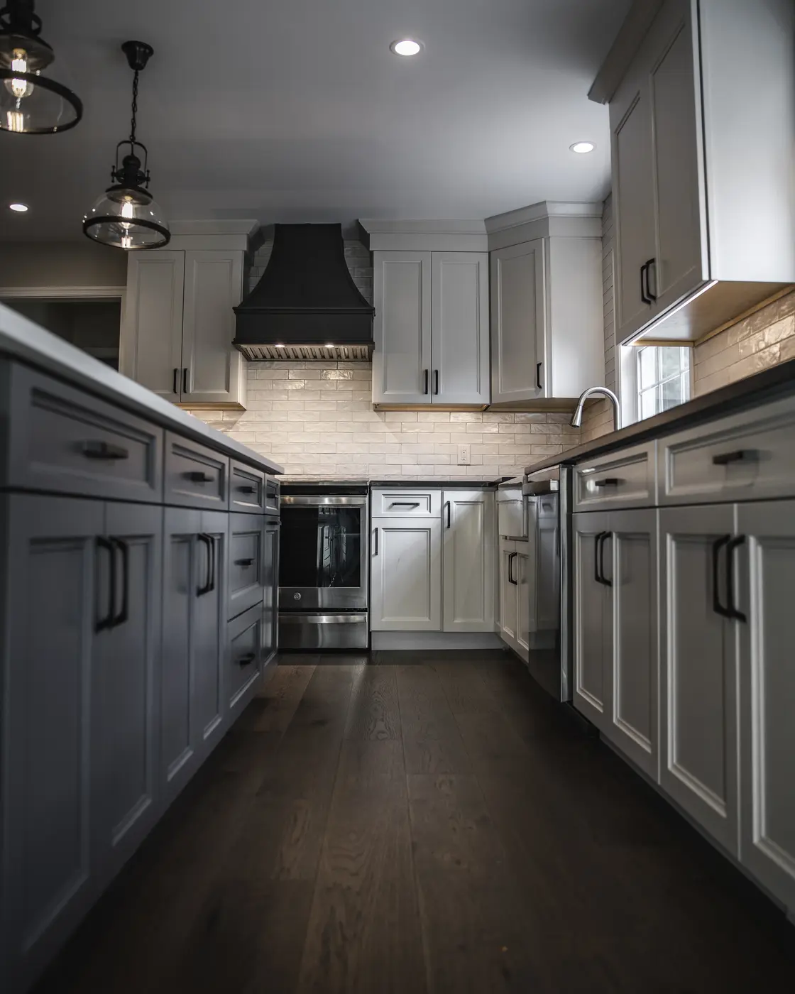 Kitchen design with two-tone cabinetry, a black vent hood, white upper cabinets, and dark hardwood floors